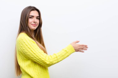 Genç, güzel bir kadın gülümsüyor, sizi selamlıyor ve başarılı bir anlaşma için el sıkışmayı teklif ediyor, işbirliği konsepti.