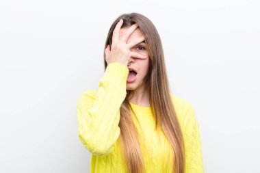 Genç, güzel bir kadın şok olmuş, korkmuş ya da korkmuş görünüyor. Yüzü elle kaplanmış ve parmaklarının arasından gizlice bakıyor.