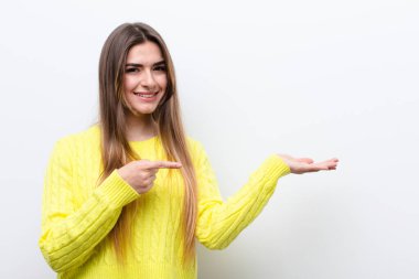 Genç, güzel bir kadın gülümsüyor, mutlu, kaygısız ve tatmin olmuş hissediyor, fotokopi alanındaki konsepte veya fikre işaret ediyor.