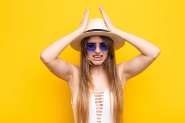 Genç ve güzel bir kadın stresli ve endişeli, depresif ve hayal kırıklığına uğramış hissediyor, iki elini de başa kaldırıyor.