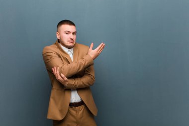 Genç yakışıklı iş adamı kafası karışık ve bilgisiz hissediyor, şüpheli bir açıklamayı merak ediyor ya da düz arkaplan hakkında düşünüyor.