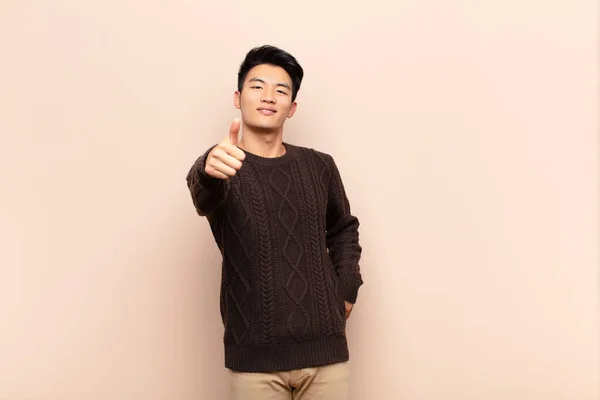 年轻的中国男人感到自豪 无忧无虑 对着平坦的彩墙竖起大拇指 面带微笑 — 图库照片