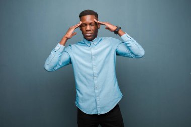 Genç Afro-Amerikan siyahi adam konsantre, düşünceli ve ilham verici görünüyor, beyin fırtınası yapıyor ve hayal kuruyor.