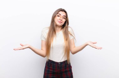 Genç, güzel bir kadın kafası karışmış ve kafası karışmış hissediyor. Doğru cevap ya da karardan emin değil. Beyaz duvara karşı bir seçim yapmaya çalışıyor.