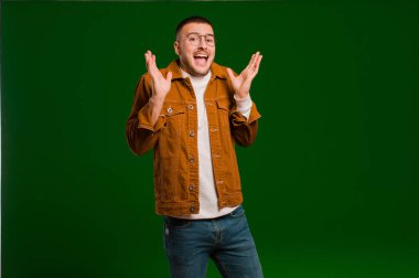 Genç yakışıklı adam şok olmuş ve heyecanlı, gülüyor, şaşırmış ve mutlu çünkü düz arkaplanda beklenmedik bir sürpriz var.
