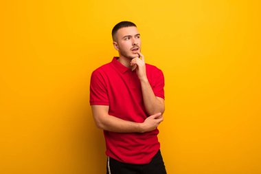 Şaşırmış, gergin, endişeli ya da korkmuş bakışları olan genç yakışıklı bir adam düz arkaplana karşı fotokopi odasına bakıyor.