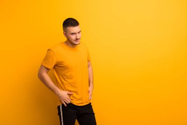 Genç, yakışıklı, gururlu, kendine güvenen, havalı, küstah, küstah, gülümseyen, düz arkaplan karşısında başarılı hisseden bir adam.