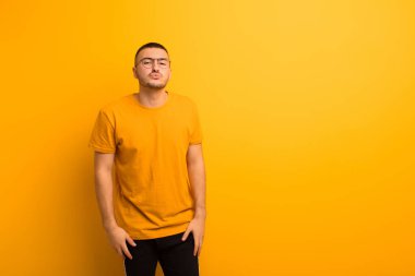 Genç yakışıklı adam dudaklarını birbirine bastırıyor, tatlı, eğlenceli, mutlu, sevimli bir yüz ifadesiyle, düz arkaplana öpücük yolluyor.