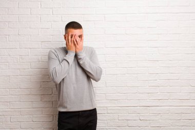 Genç ve yakışıklı bir adam korkmuş ya da utanmış hisseder, dikizler ya da gözleri yarı çıplak bir şekilde duvara bakar.