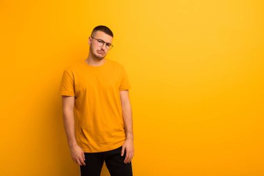 Genç ve yakışıklı bir adam kafası karışık ve kuşkulu, merak ediyor ya da düz arkaplan karşısında karar vermeye çalışıyor.