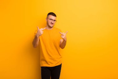 Genç yakışıklı adam kışkırtıcı, agresif ve müstehcen hissediyor, orta parmağını oynatıyor, düz arkaplana karşı isyankar bir tavırla