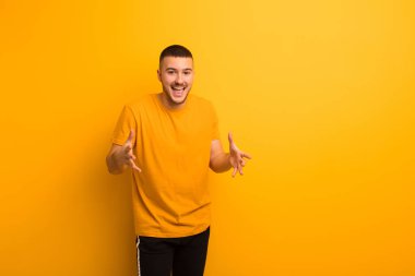 Genç yakışıklı adam kendini mutlu, şaşkın, şanslı ve şaşırmış hissediyor. Düz arkaplan karşısında inanılmaz