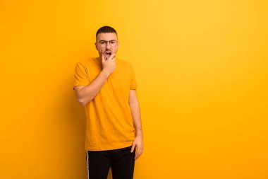 Ağzı ve gözleri açık, eli çenesinde genç ve yakışıklı bir adam, nahoş bir şokta, düz arkaplan karşısında ne ya da wow diyor