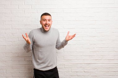 Genç yakışıklı adam mutlu, heyecanlı, şaşırmış ya da şaşırmış hissediyor, gülümsüyor ve şaşırıyor.