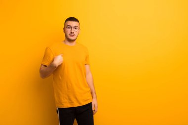 Kafası karışmış, kafası karışmış ve kendine güveni olmayan genç yakışıklı bir adam kendini gösterip kim olduğumu soruyor, ben mi? düz arkaplan