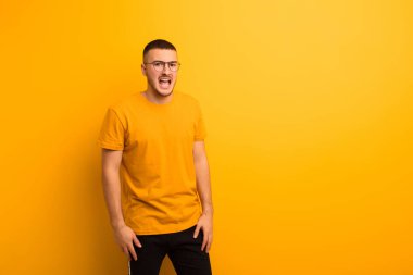 Genç yakışıklı adam korkmuş ve şok olmuş hissediyor, ağzı açık düz arkaplan karşısında şaşkınlık içinde.