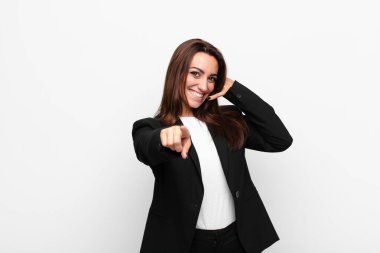 Genç ve güzel iş kadını neşeli bir şekilde gülümsüyor ve kamerayı işaret ediyor. Daha sonra seni arıyor, telefonda beyaz duvara karşı konuşuyor.