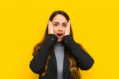 Genç, güzel bir kadın mutsuz, korkmuş ya da endişeli görünüyor, ağzı sonuna kadar açık ve iki kulağını da el işi ya da iş konseptiyle kapatıyor.