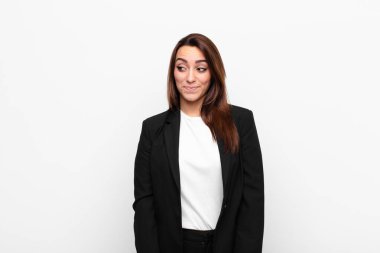 Genç ve güzel iş kadını merak ediyor, mutlu düşünceler ve fikirler düşünüyor, hayal kuruyor, beyaz duvara karşı uzayı kopyalamaya çalışıyor.