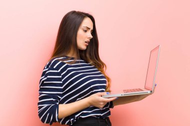 Genç ve güzel bir kadın dizüstü bilgisayar tutuyor.