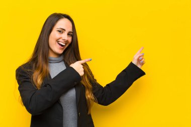 Genç ve güzel bir kadın sevinçli ve şaşırmış hissediyor, şok olmuş bir ifadeyle gülümsüyor ve ek iş ya da iş konseptine işaret ediyor.