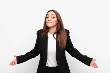 Genç ve güzel bir iş kadını, hiçbir fikri olmadan, cahil ve kafası karışık hissediyor, beyaz duvara bakan aptal veya aptal bir bakışla tamamen şaşkına dönmüş.