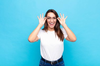 Genç, güzel bir kadın şok olmuş, şaşırmış ve şaşırmış hissediyor. Elinde hayret dolu, inanmayan bir bakışla mavi duvara bakıyor.