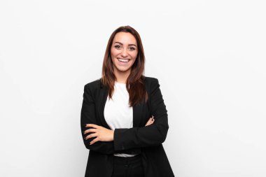 Genç, güzel bir iş kadını gibi görünen mutlu, gururlu ve tatmin olmuş kollarını beyaz duvara dolamış bir şekilde gülümseyen