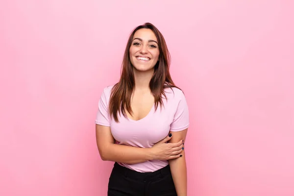恥ずかしがり屋で陽気に笑う若い可愛い女性ピンクの壁に対してフレンドリーで肯定的ではあるが安全ではない態度で — ストック写真