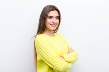 Genç ve güzel bir kadın kameraya çapraz kollarıyla gülümsüyor ve mutlu, kendinden emin, tatmin olmuş bir ifade, yan bakış.