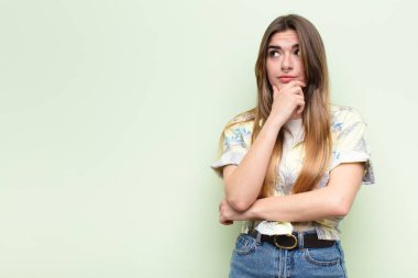 Genç, güzel bir kadın düşünüyor, kuşkulu ve şaşkın hissediyor, farklı seçeneklerle, turist konsepti yapmak için hangi kararı vereceğini merak ediyor.