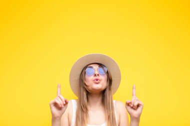 Genç ve güzel bir kadın huşu içinde ve ağzı açık bir şekilde şaşkın ve şaşkın bir bakışla yukarıya bakıyor.