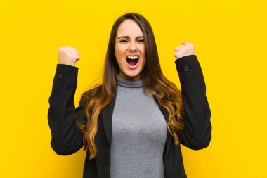 Genç ve güzel bir kadın sinirli bir ifadeyle ya da başarılı bir işi ya da iş kavramını kutlarken yumruklarını sıkarak agresif bir şekilde bağırıyor.