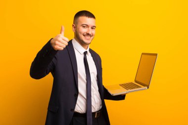 Genç ve yakışıklı bir iş adamı dizüstü bilgisayar tutuyor.