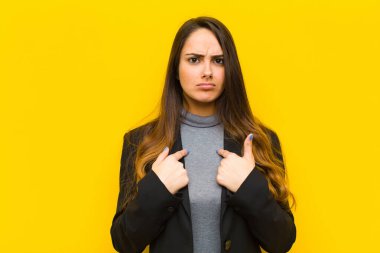 Genç ve güzel bir kadın, şaşkın ve hızlı bakışlarıyla kendini işaret ediyor. İş ya da iş konsepti seçildiği için şaşırmış ve şaşırmış görünüyor.