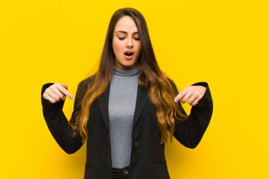 Genç, güzel bir kadın şoke olmuş, ağzı açık ve şaşırmış, inançsızlığa ve sürpriz işe veya iş konseptine bakıyor ve onları işaret ediyor.