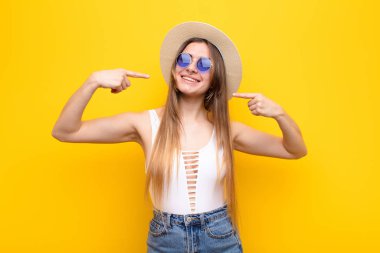 Genç, güzel bir kadın, kendine güvenerek gülümsüyor. Kendi gülüşünü gösteriyor. Olumlu, rahat, tatmin olmuş bir tavır.