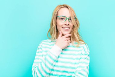 Genç, güzel sarışın kadın gülümsüyor, hayattan zevk alıyor, mutlu, arkadaş canlısı, tatmin olmuş ve tasasız.