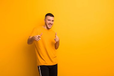 Genç yakışıklı adam kendini mutlu, sakin, tatmin olmuş, rahat ve başarılı hissediyor, kameraya bakıyor, düz arkaplana karşı seni seçiyor.