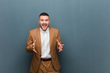 Genç yakışıklı adam kendini mutlu, şaşkın, şanslı ve şaşırmış hissediyor. Düz duvara karşı inanılmaz.