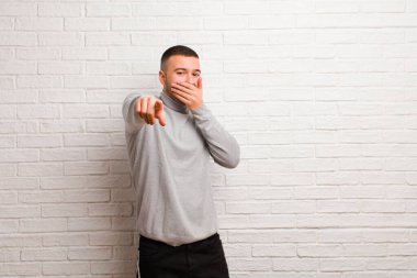 Genç yakışıklı adam sana gülüyor, kamerayı işaret ediyor ve seninle dalga geçiyor ya da arka planda alay ediyor.