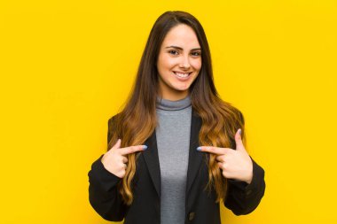 Genç ve güzel bir kadın gururlu, pozitif ve ilgisiz görünüyor. İki eliyle ya da iş konseptiyle göğsünü gösteriyor.