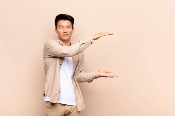 Jovem Chinês Sorrindo Sentindo Feliz Positivo Satisfeito Segurando Mostrando Objeto — Fotografia de Stock