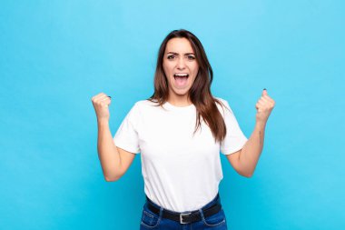 Genç ve güzel bir kadın öfkeli bir ifadeyle ya da mavi duvara karşı başarıyı kutlayan yumruklarla agresif bir şekilde bağırıyor.