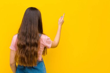 Genç, güzel bir kadın dikiz aynasındaki nesneyi işaret ediyor.