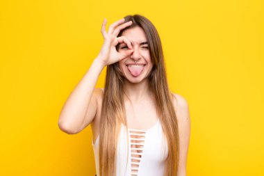 Genç ve güzel bir kadın mutlu bir şekilde gülümsüyor, şaka yapıyor ve gözetleme deliğinden bakıyor, sırları gözetliyor.