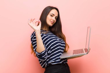 Genç ve güzel bir kadın dizüstü bilgisayar tutuyor.