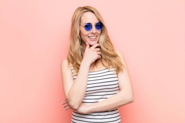 Genç, güzel sarışın kadın gülümsüyor, hayattan zevk alıyor, mutlu, arkadaş canlısı, tatmin olmuş ve tasasız.