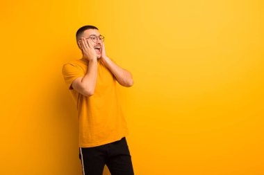 Genç yakışıklı adam mutlu, heyecanlı ve şaşırmış hissediyor, iki eli de düz arkaplanda yana bakıyor.