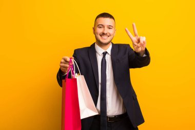 Genç ve yakışıklı iş adamı, arka planda alışveriş torbalarıyla.